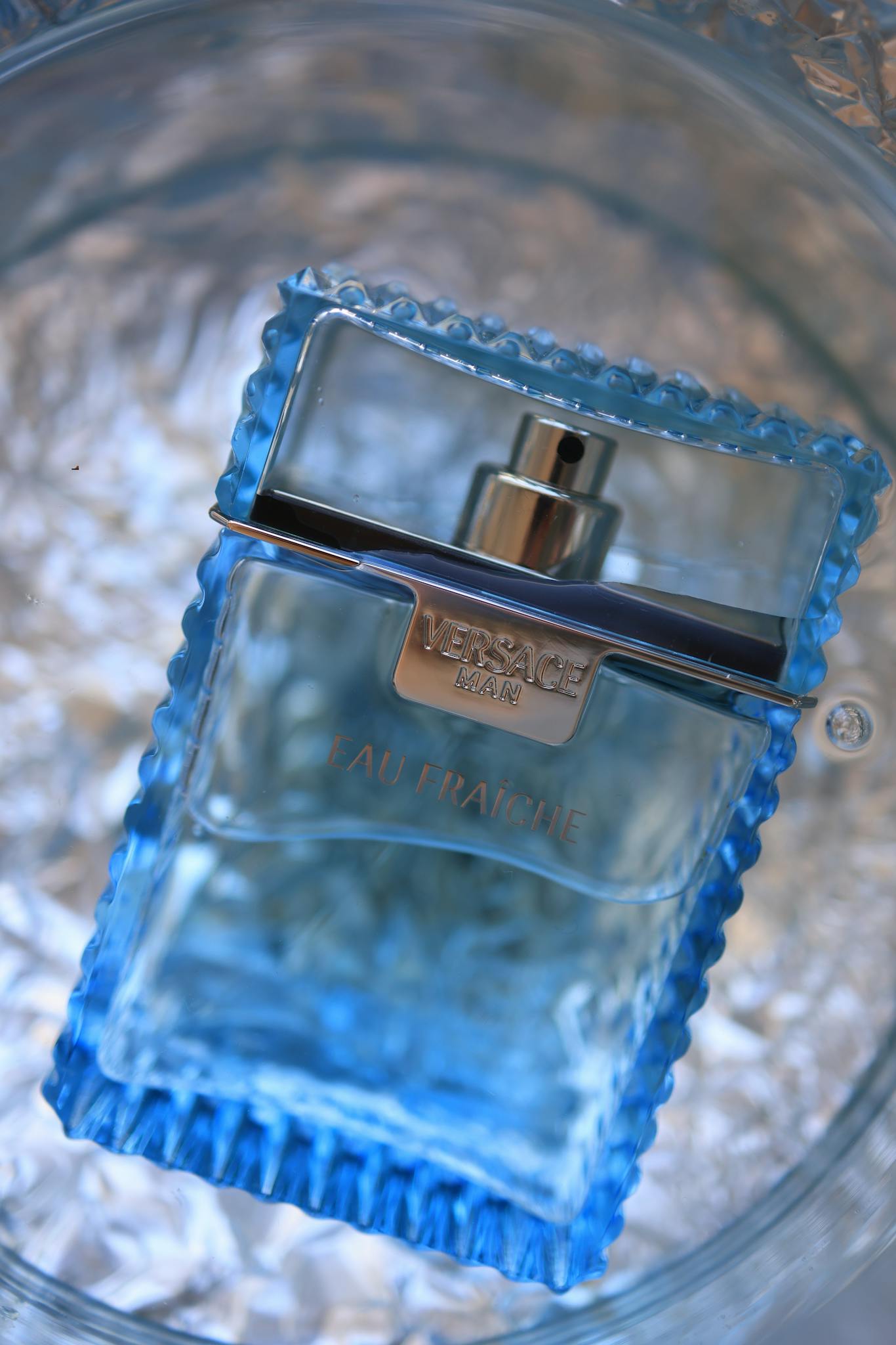 Close-up of a luxury blue perfume bottle on a textured background, showcasing elegance and fragrance.