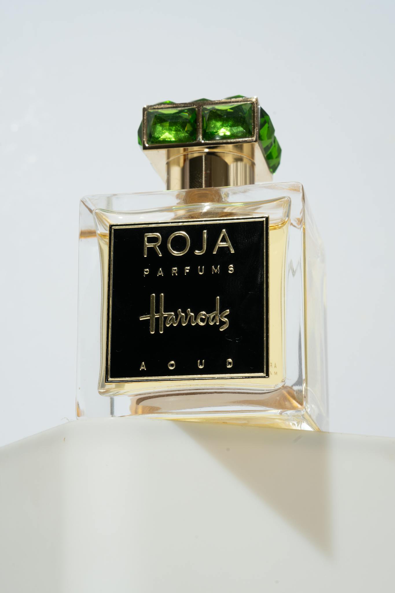 Elegant Roja Parfums Harrods Aoud bottle with green gem cap, showcasing luxury fragrance.